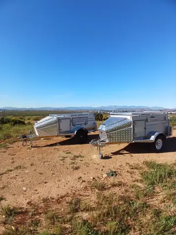 Two Tracker trailers in the veld under a blue sky