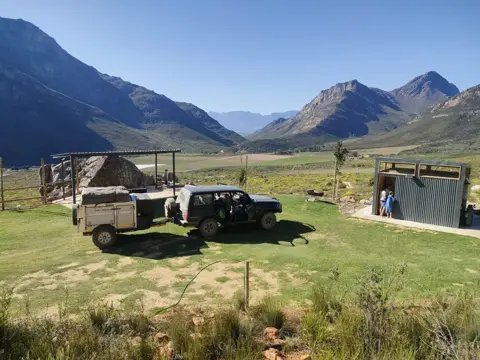 XK6 camper trailer hitched to a 4x4 in a mountain valley